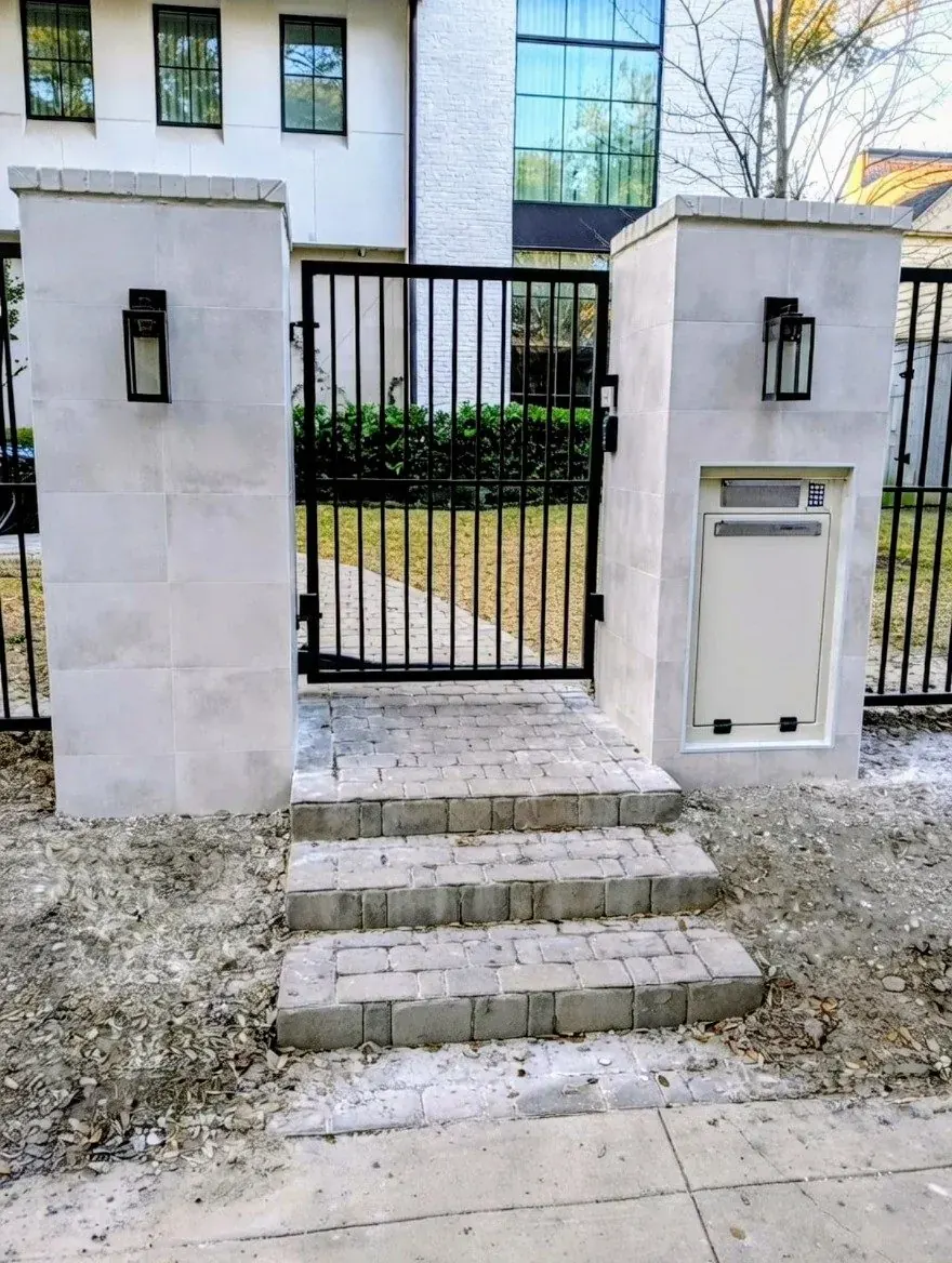 White stone columns with a black metal walk gate and steps