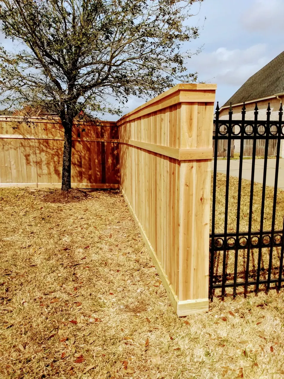 Cedar privacy fence meeting a black ornamental iron gate at a Cross Creek Ranch home in Fulshear