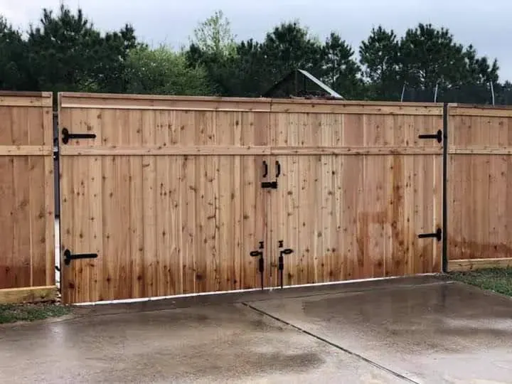 Large swinging double wood driveway gate with black hardware