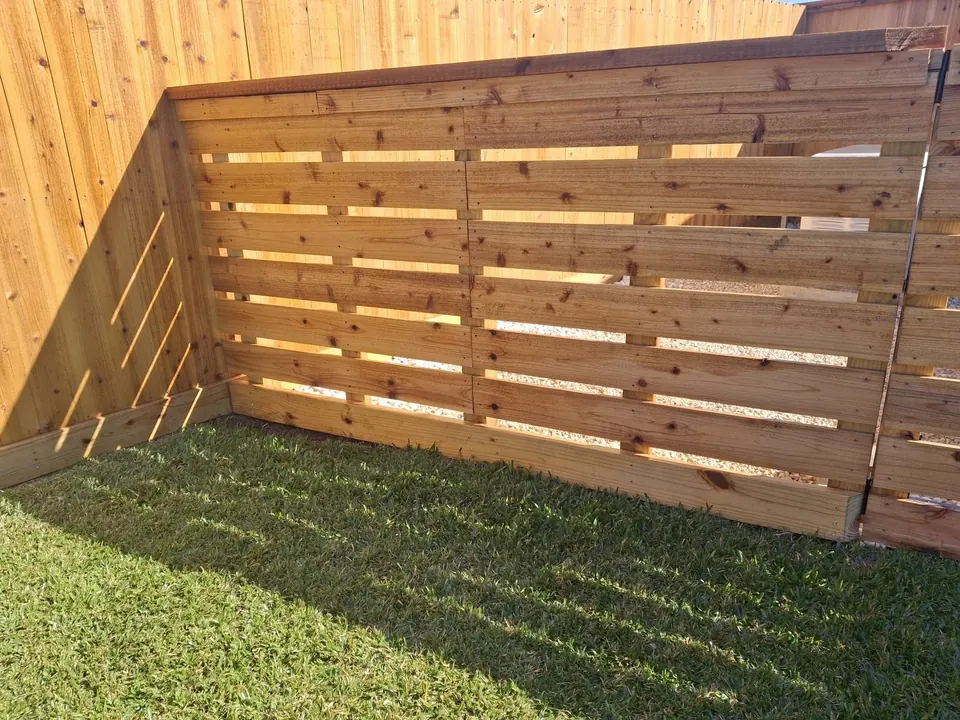 Horizontal cedar-slat privacy fence corner in a backyard