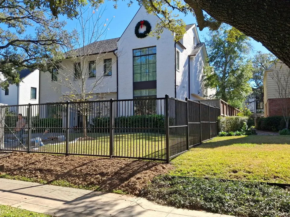 Black ornamental metal fence in front of a modern white home