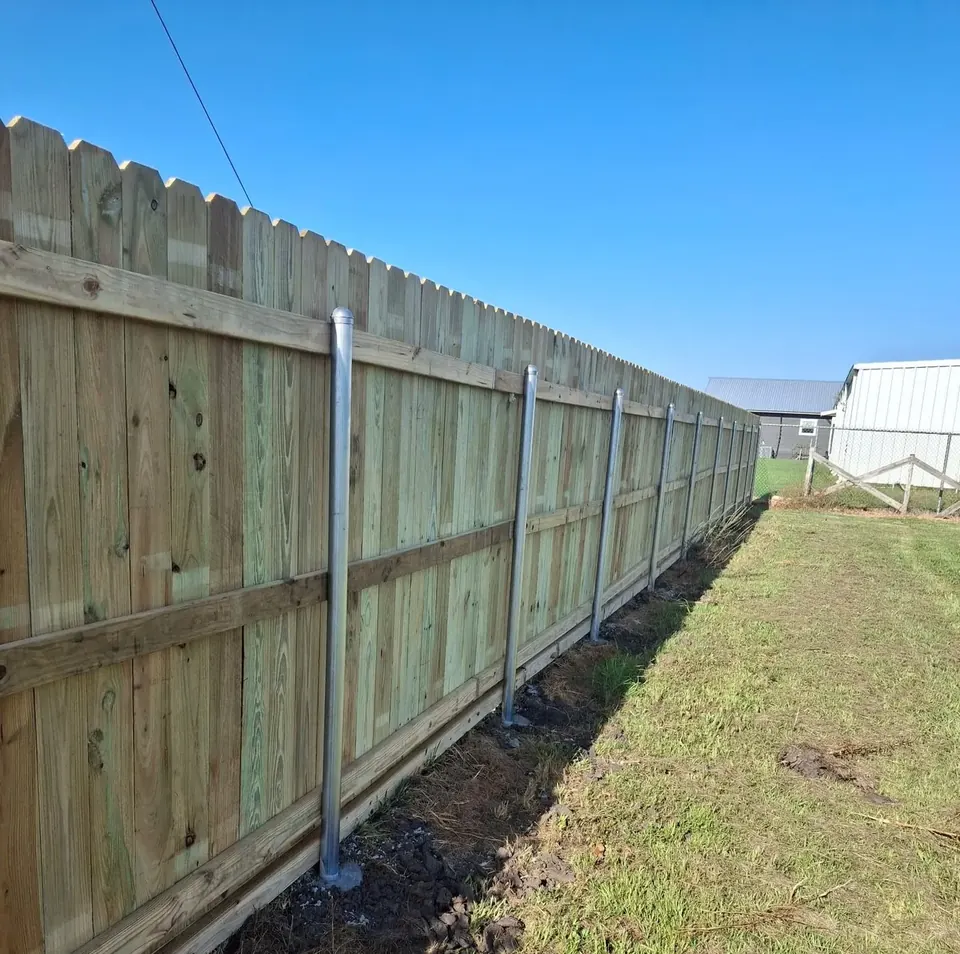 Long pressure-treated pine privacy fence on steel posts in Fulshear