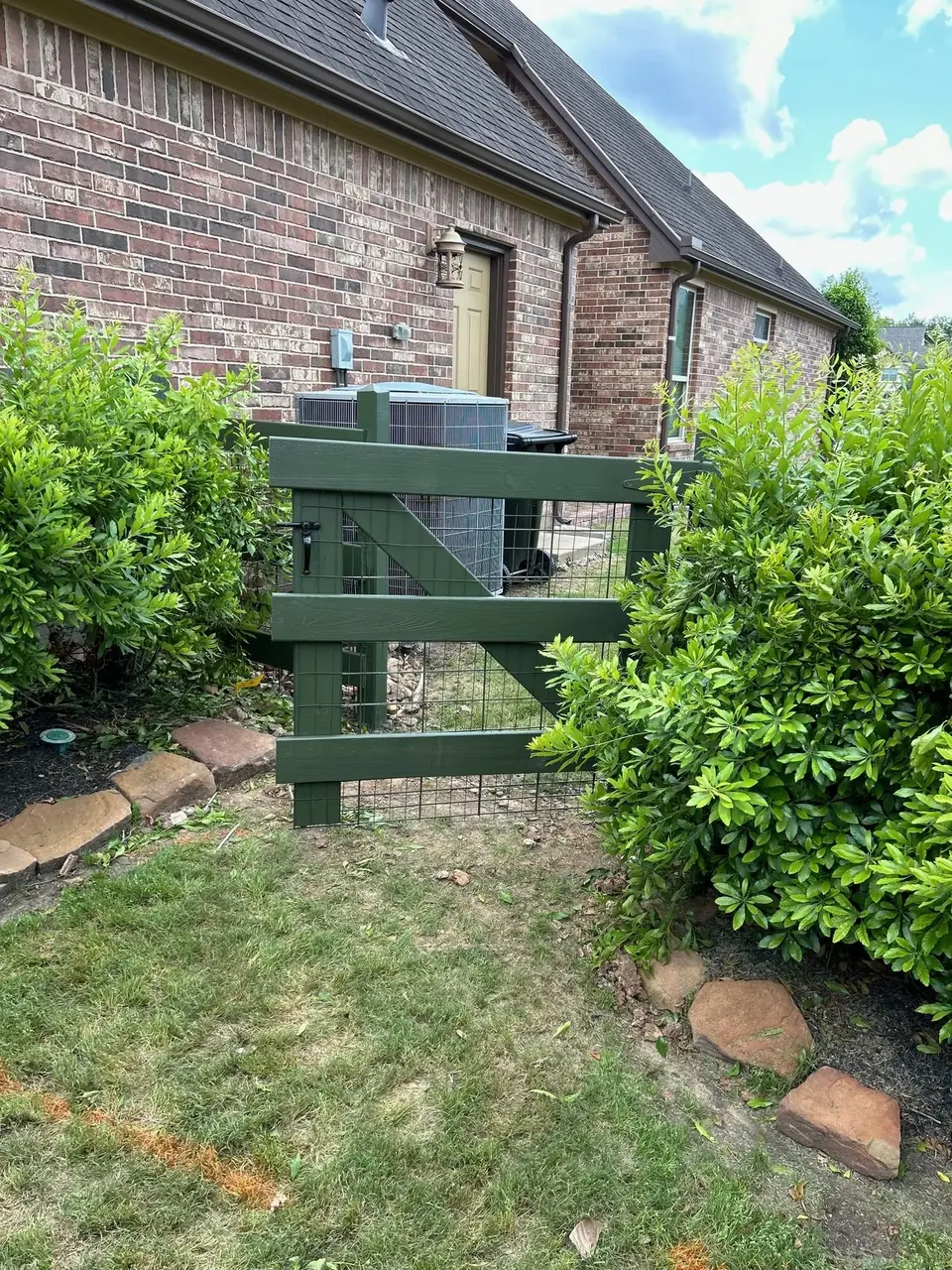 Green-painted rail fence and gate beside a brick home in Fulbrook on Fulshear Creek