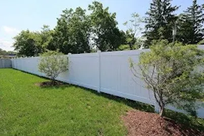 White vinyl privacy fence along a green lawn